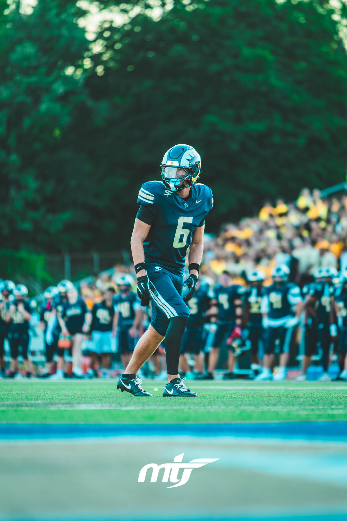 Player walking onto the field past his teammates lined up before kickoff