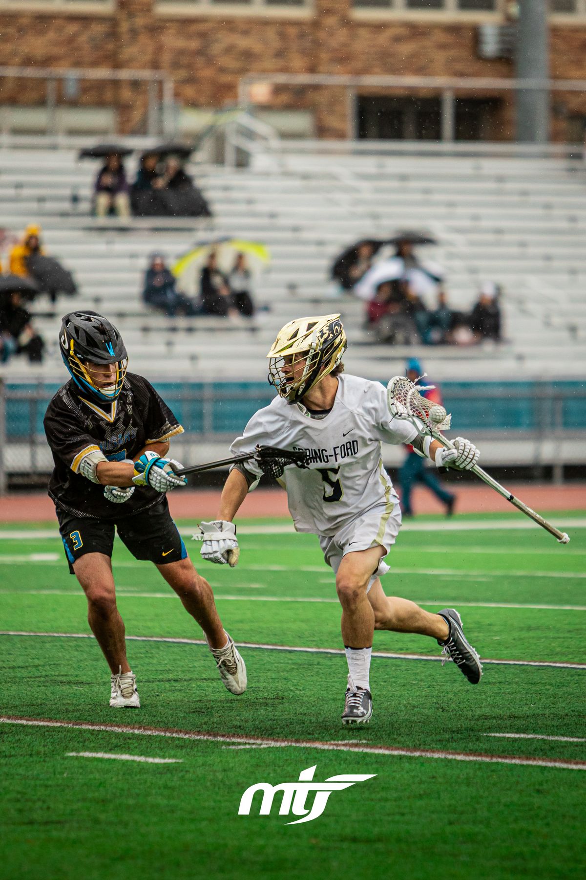 Two lacrosse players battling for the ball in the rain
