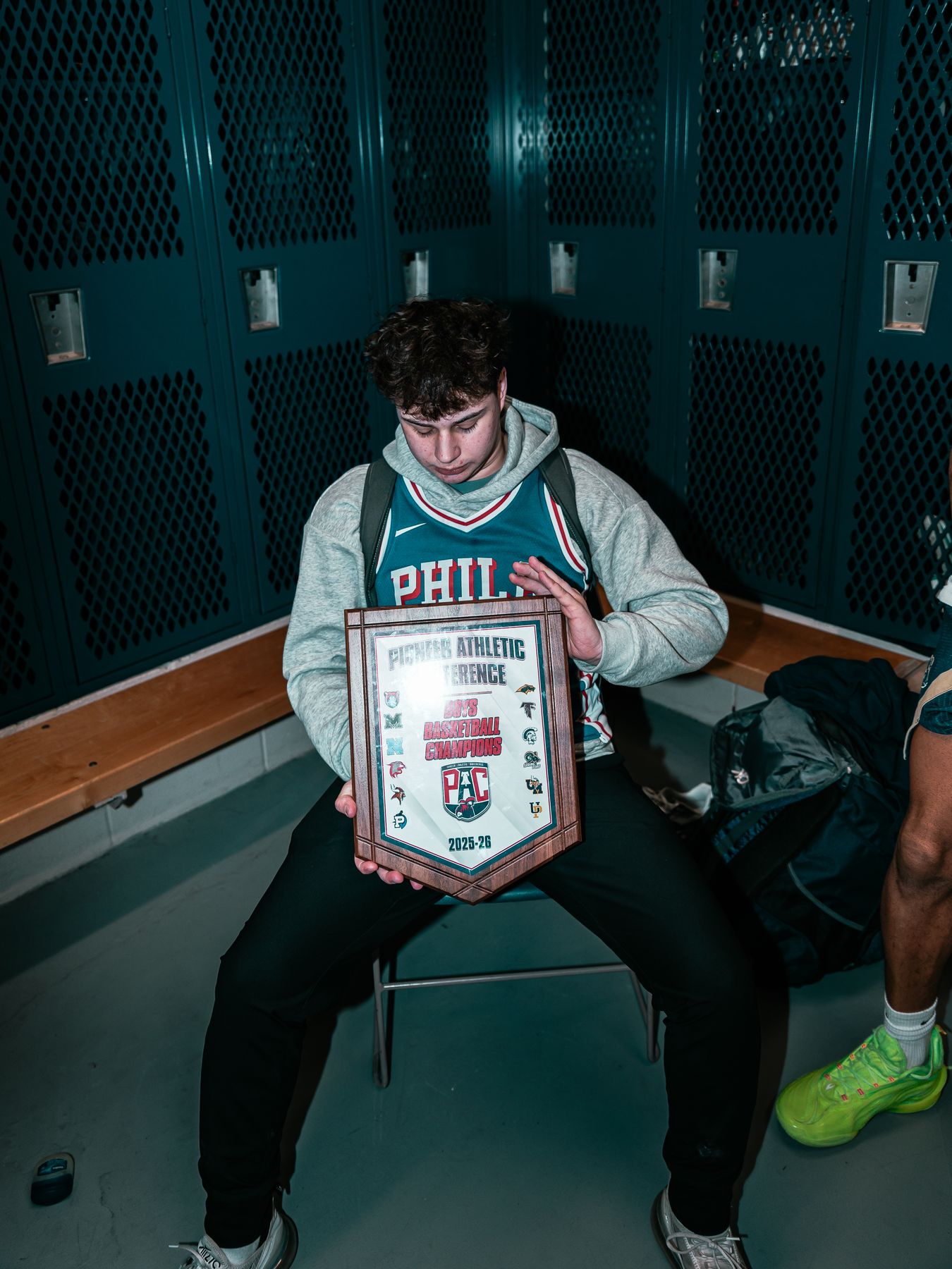 Max in the locker room with the Pioneer Athletic Conference championship plaque